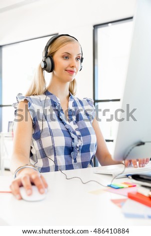 Young woman listening to the music while working on a computer