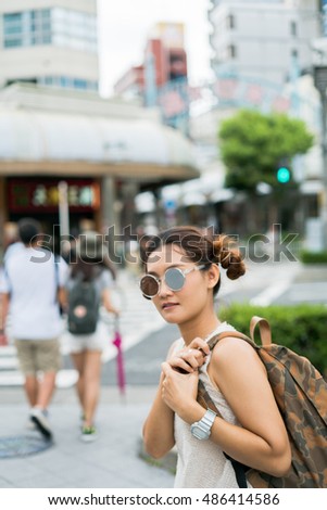 Young pretty Asian girl posing on the street  with camera travel photo of photographer Making pictures in hipster style glasses on the street  , Japan