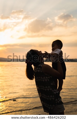 mother and son are very happy.they go to the seashore together in the evening. they like to see sunset.baby is being carried by mother.mother loves her son.she is always happy when they play together.