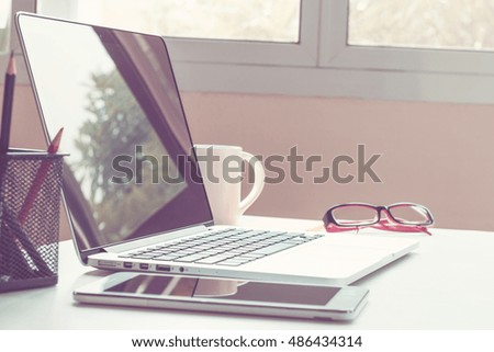 Office desk with laptop smart phone and business office background, vintage effect, selective focus