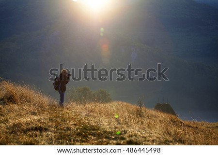 Photographer taking photos in autumn mountains in sunrise
