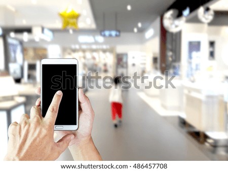 Girl use mobile phone, blur image of inside the mall as background.