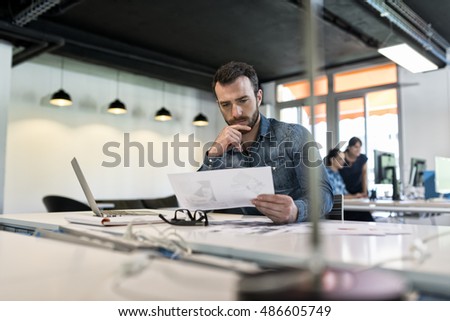 Man in modern office start-up working on laptop. Royalty-Free Stock Photo #486605749