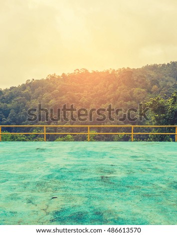 vintage tone image of empty cement floor and green forest with sunlight in background.