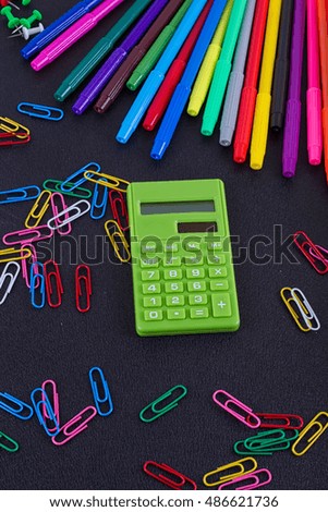 calculator, paper clips, markers on black Board. School and business concept