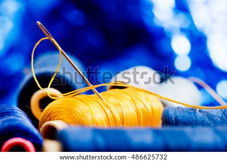needle and yellow thread on the blue background
