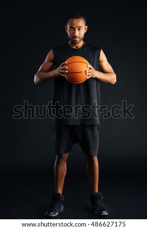 Attractive young african man with basket ball isolated on a black background