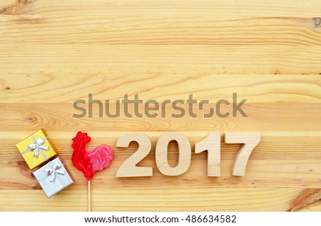 Red rooster, symbol of 2017 on the Chinese calendar. Lollipop in the form of a red rooster on a wooden background