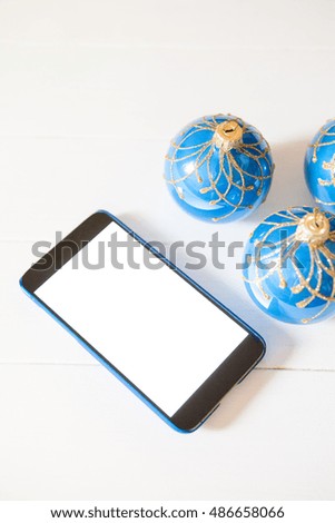 Christmas smartphone mockup. Mobile phone and blue balls on white background with copy space. Online gift buying. Top view, flat lay.