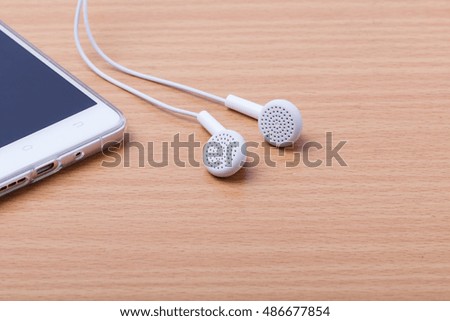 White headphones for smartphone on wood background