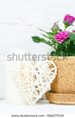 Decorative heart, pink roses and candles on white wooden background. Selective focus. Place for text.