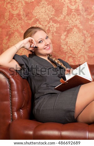 Young business woman sitting on the couch with a notebook in hands