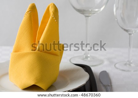 Selective focus image of a feastful decorated Easter table with a napkin folded as rabbit.