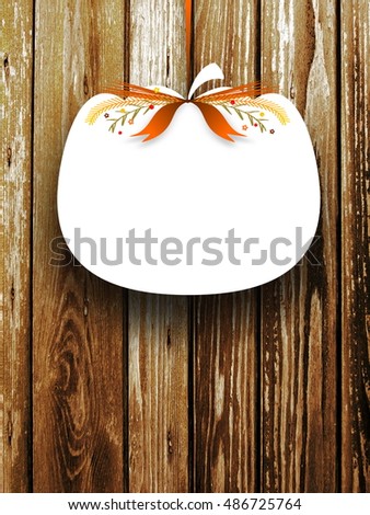Close-up of one blank pumpkin shaped frame hanged by brown ribbon on brown wooden boards background