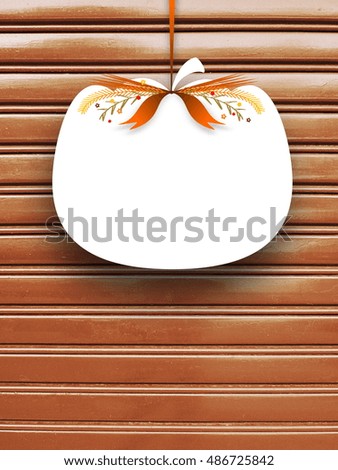 Close-up of one blank pumpkin shaped frame hanged by brown ribbon on brown metal shutter background