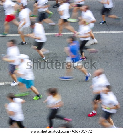 People in white T-shirts running half marathon on city streets in attentional motion blur