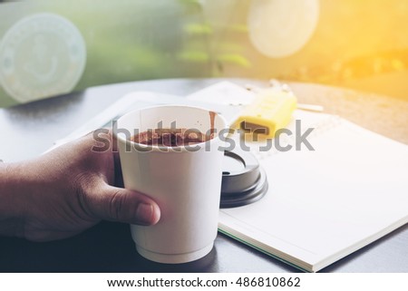 Good morning sunrise image of the hand hold a cup of morning beverage with note book and car key background 