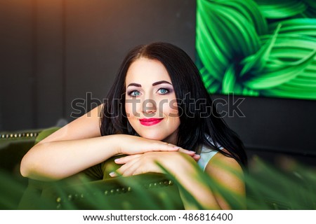Beautiful brunette girl with blue eyes on a background of the room and picture