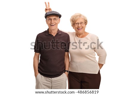 Elderly woman pranking her husband with bunny ears isolated on white background