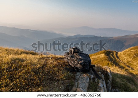 The camera rests on a backpack on the rocks at the mountains background