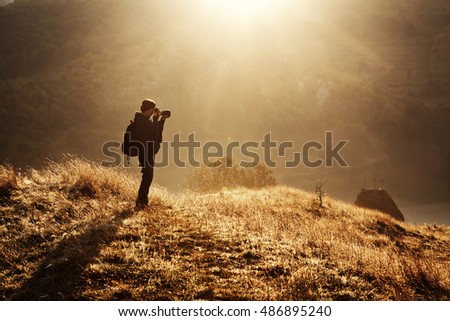 Woman photographer in the mountains on an early autumn mornining