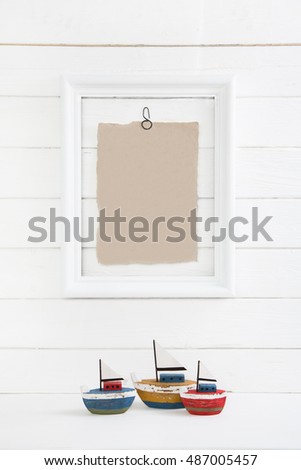 Three sail boast on a white wooden background with a picture frame in mock up style empty and nobody for concepts.