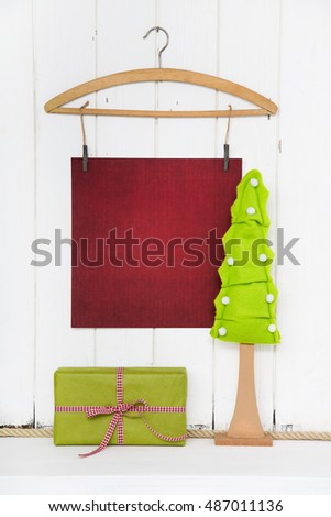 Christmas empty wooden background with a tree and a sheet of paper and a red green gift for coupon certificate in mock up style.