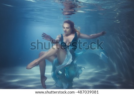 Woman in a dress dives underwater, she dances on the bottom. Royalty-Free Stock Photo #487039081