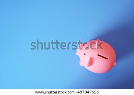 piggy bank save coin, blue desk background, copy space on Left side Royalty-Free Stock Photo #487049656