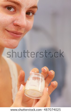 Woman applying mask moisturizing skin cream on face in bathroom. Girl taking care of her complexion layering moisturizer. Skincare spa treatment. 