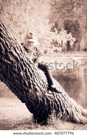 Girl sitting on a tree near the lake in spring Park