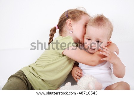 Cute older sister giving a kiss to her brother