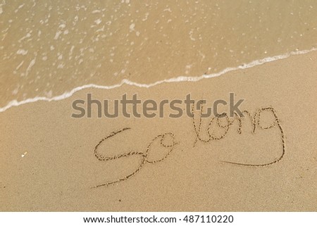 written words "So long" on sand of beach