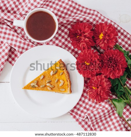 Pumpkin pie on the table. Autumn menu. Homemade baking. Bunch of red dahlia. Breakfast. Tea. Piece of cake.