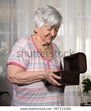 Old woman with present box posing at home 