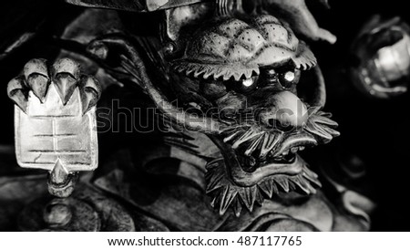 Black and white style of Chinese Dragon Statue under foot of Guanyin Buddha statue with light dark background. Buddha image used as amulets of Buddhism religion.