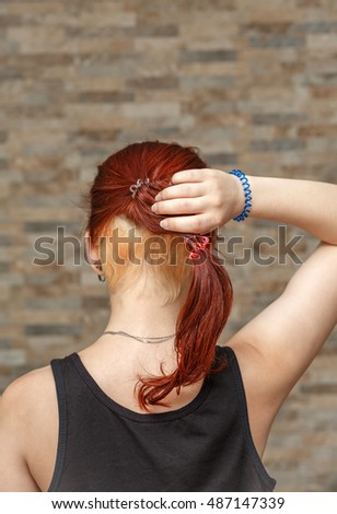 young model holding colored tail with hidden undercut bleached hair with elastic band arm. photo with shallow depth of field
