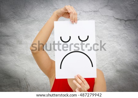 Woman holding a paper sheet with a frown emoticon