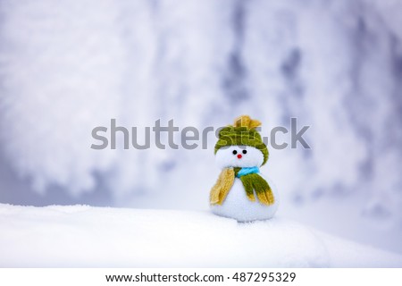 On the white fluffy textured snow alone snowman the friend is standing in nice hat and scarf with red nose.