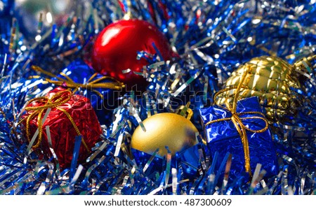 Christmas ornament closeup photo. Red and gold ball. Golden pine. Blue and red wrapped gifts. Sparkling ribbon on background. Picture for New Year greeting card, seasonal holiday banner template