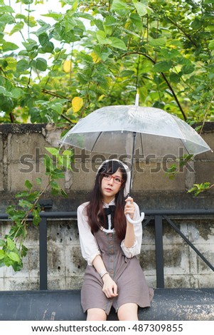 Charming Asian girl with umbrella in raining day