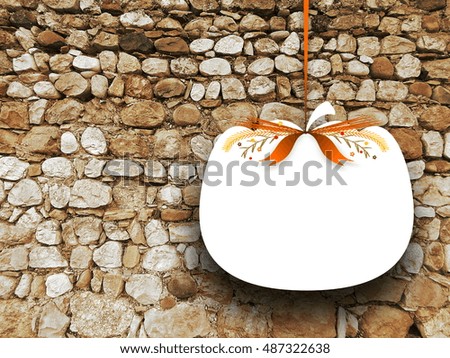 Close-up of one blank pumpkin shaped frame hanged by brown ribbon on ancient old stone wall background