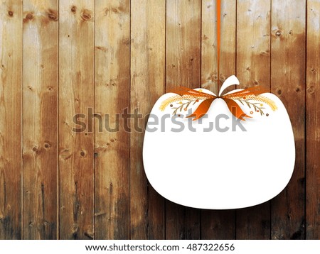 Close-up of one blank pumpkin shaped frame hanged by brown ribbon on vertical wooden boards background