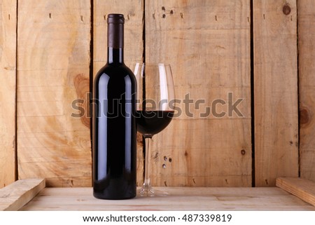 Red wine glass and bottle over a textured wood background Royalty-Free Stock Photo #487339819