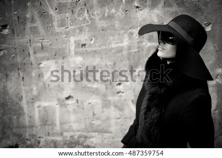 Black and white picture of mysterious lady in black coat and glasses on her face