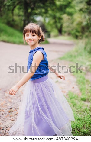 beautiful and small girl walking in the green garden