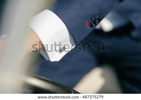 Silver cufflink on the white shirt of the groom