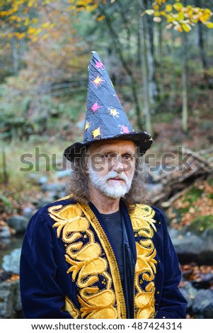 Portrait of old mysterious wizard having a rest in deep autumn forest