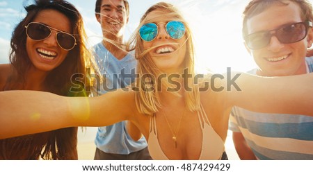 Happy group of friends having fun taking a picture together on the beach