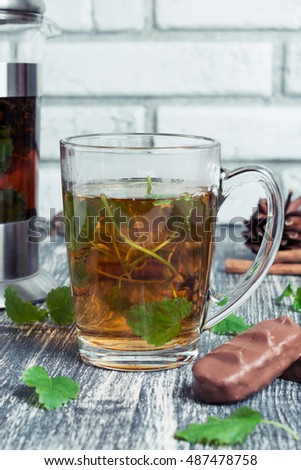 Cup of tea on a wooden background. Hot mint tea with chocolate and candy on old table